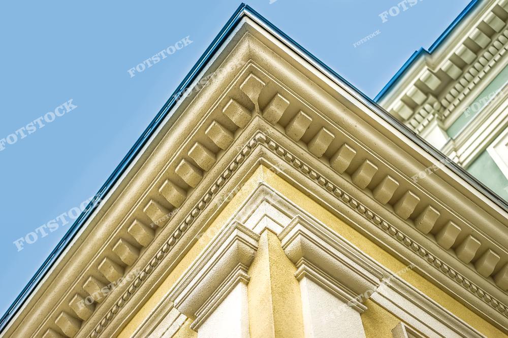На изображении показана лепнина на фасаде здания, представляющая собой intricately проработанные декоративные элементы. Это отделка здания, подчеркивающая его архитектурную красоту и элегантность. Лепные украшения добавляют уникальности и исторического характера архитектуре.