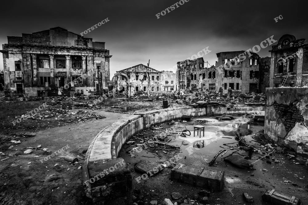 На фотографии изображен разрушенный городской ландшафт, снятый в черно-белом стиле. Полуразрушенные здания, обломки и пустота передают мрачное настроение и последствия катастрофических событий. Снимок символизирует упадок и историческую трагедию, оставившую свой отпечаток на городской архитектуре.