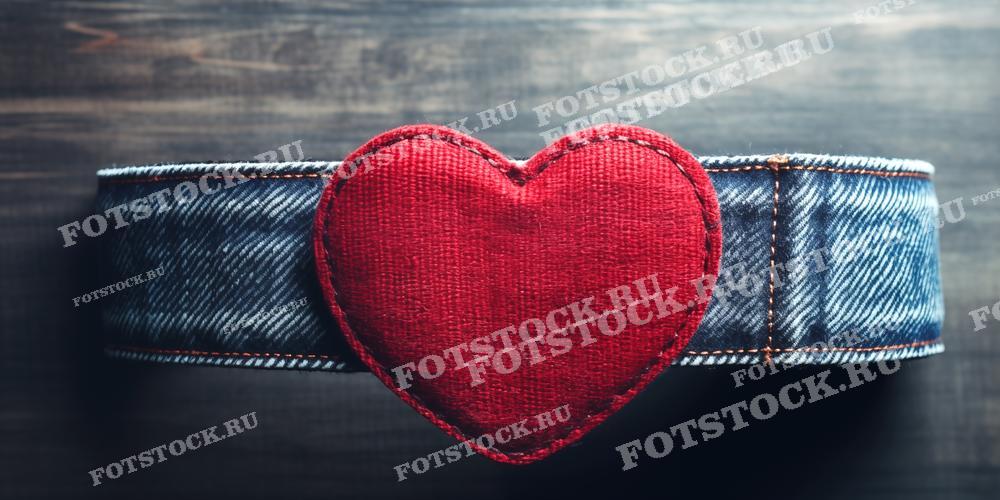 На фотографии изображено красное сердце, выполненное из ткани и прикрепленное к джинсовому ремню на фоне темной поверхности. Это изображение может быть использовано в рекламных и маркетинговых материалах, особенно в контексте моды и аксессуаров, а также в кампаниях, связанных с Днем Святого Валентина или другими романтическими праздниками. Фотография также подойдет для использования в статьях и блогах о моде, ремесленных изделиях и подарках.