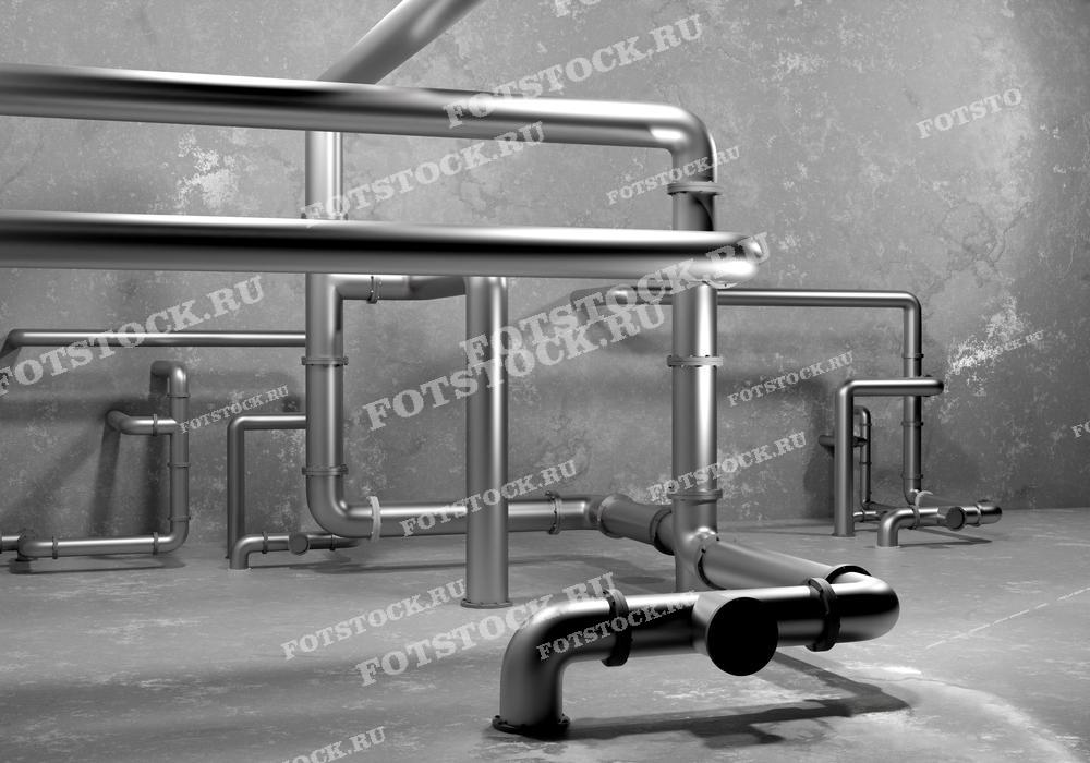 На фотографии изображены металлические трубопроводы, установленные вдоль бетонной стены. Трубы составляют часть инженерных коммуникаций, необходимых для функционирования промышленного или жилого помещения.
