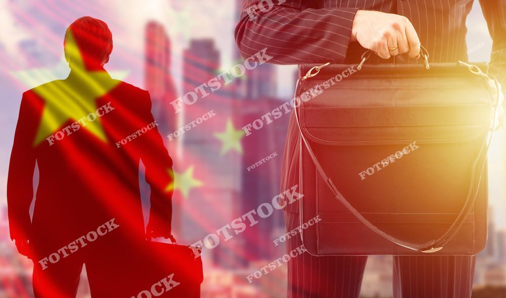 На изображении силуэт бизнесмена на фоне китайского флага и урбанистического пейзажа. Рядом крупным планом показан мужчина с портфелем в строгом костюме. Снимок символизирует роль Китая в мировой экономике, деловую активность и международные инвестиции.