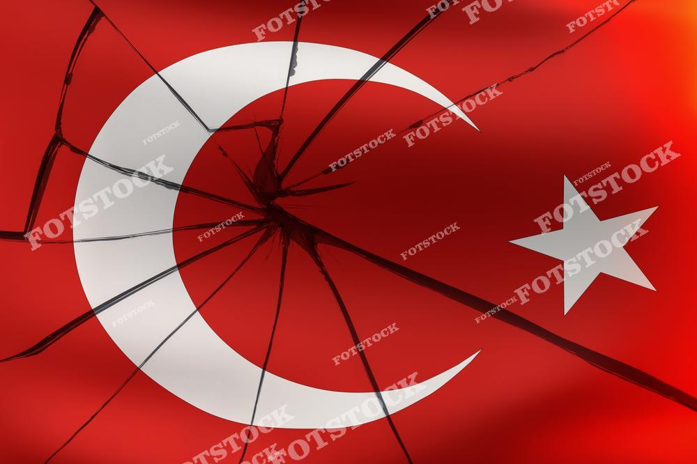 На изображении турецкий флаг с наложенными трещинами, создающими эффект разрушения. Яркий красный фон с полумесяцем и звездой контрастирует с трещинами, символизируя проблемы или трудности. Фото может ассоциироваться с политической, социальной или экономической нестабильностью.