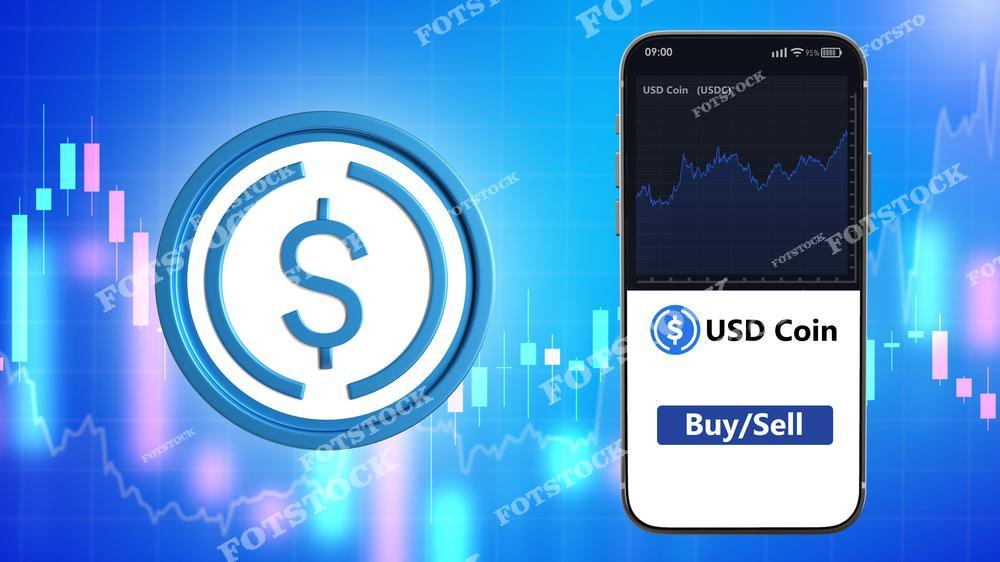 На изображении крупный символ USD Coin, а рядом смартфон с графиком, отображающим динамику стоимости. Фон из графиков и цифровых линий создает атмосферу трейдинга. Фото отражает концепцию цифровых валют, торговли и финансовых технологий.