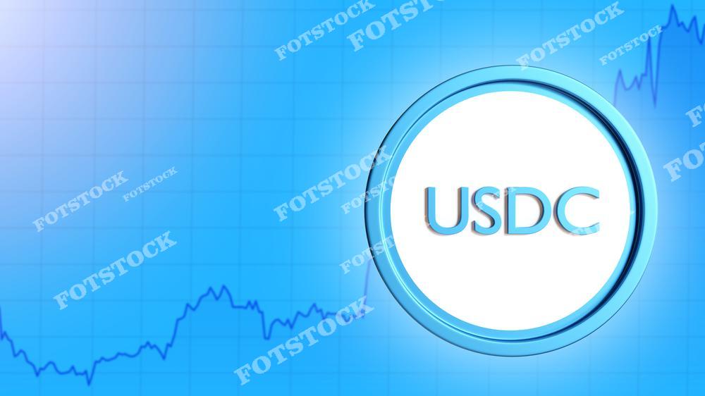 На изображении крупный символ USD Coin (USDC) на фоне синего графика. Фон с линиями динамики подчеркивает связь с финансовым рынком. Фото ассоциируется с цифровыми валютами, инвестициями и экономическими трендами.