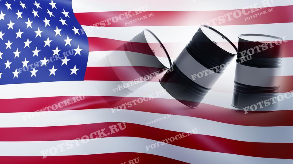 Фотография изображает флаг США и нефтяные бочки на фоне. Это символизирует важность нефтяной промышленности для экономики Соединенных Штатов. Нефтяные бочки подчеркивают роль энергетического сектора в экономике страны. Сцена ассоциируется с нефтяным рынком, производством и экспортом нефти в США.