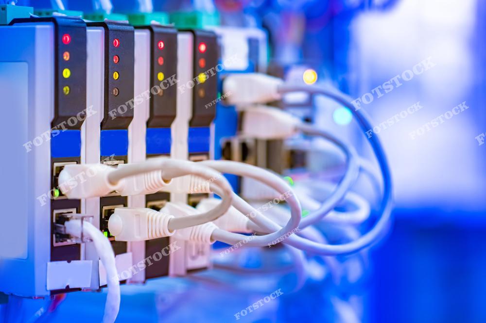 На изображении показаны сетевые устройства с подключенными Ethernet-кабелями и световыми индикаторами активности. Это оборудование используется для передачи данных в компьютерных сетях и обеспечивает подключение к интернету и другим сетевым сервисам.