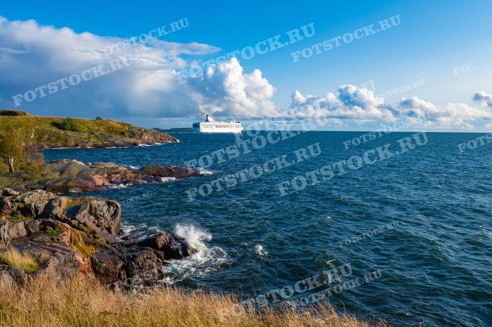 На фотографии представлен захватывающий вид на Балтийское море с скалистого берега Финляндии. Вдали виден круизный лайнер, плавно проплывающий мимо, что добавляет ощущение масштаба и движения к мирному морскому пейзажу. Скалы и волны передают дух приключений и красоту скандинавской природы. Это изображение подойдёт для туристических каталогов, путеводителей и статей, посвященных морскому путешествию и природным достопримечательностям.