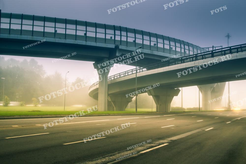 Фотография пустой городской развязки, погруженной в утренний туман. Снимок подчеркивает атмосферу спокойствия и тишины, контрастирующую с обычно оживленной городской средой.