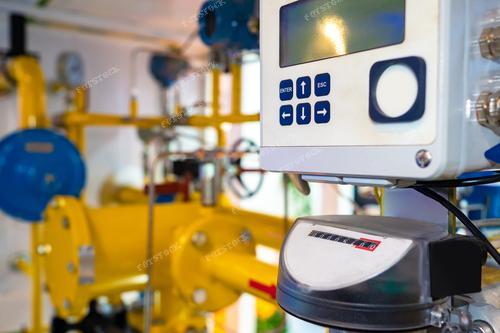 На фотографии представлены средства учета энергоресурсов на газоперерабатывающем заводе. Контрольный пульт и счетчик расположены на фоне желто-голубых труб. Эта картина иллюстрирует процессы в газовой промышленности, подчеркивая важность эффективного учета и контроля за энергетическими ресурсами. Фотография может быть использована в материалах об энергосбережении, индустриальной автоматизации, и сфере газопереработки.