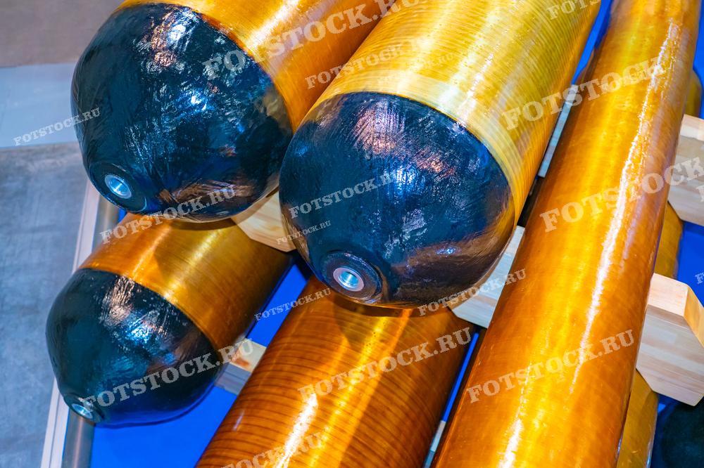 Фотография демонстрирует газовые баллоны, изготовленные из композитных материалов, уложенные в ряды. Баллоны используются для хранения и транспортировки газа в различных промышленных и бытовых условиях.