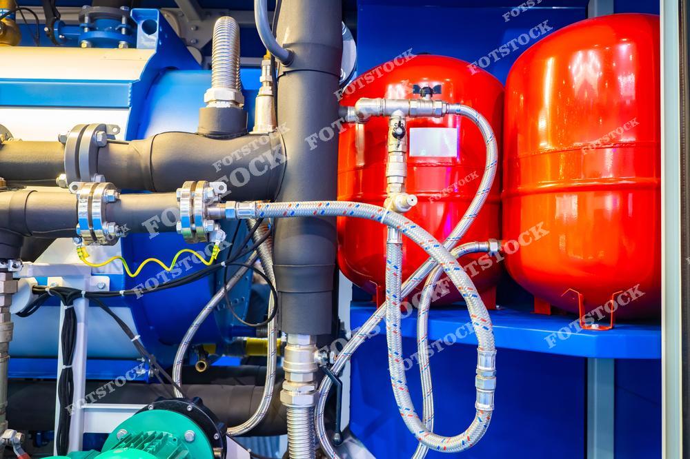 На фото изображены трубы и газовые баллоны, используемые в котельной системе для отопления дома. Фрагмент котельного оборудования демонстрирует элементы системы отопления, которая обеспечит комфортное отопление жилых помещений с использованием газа.