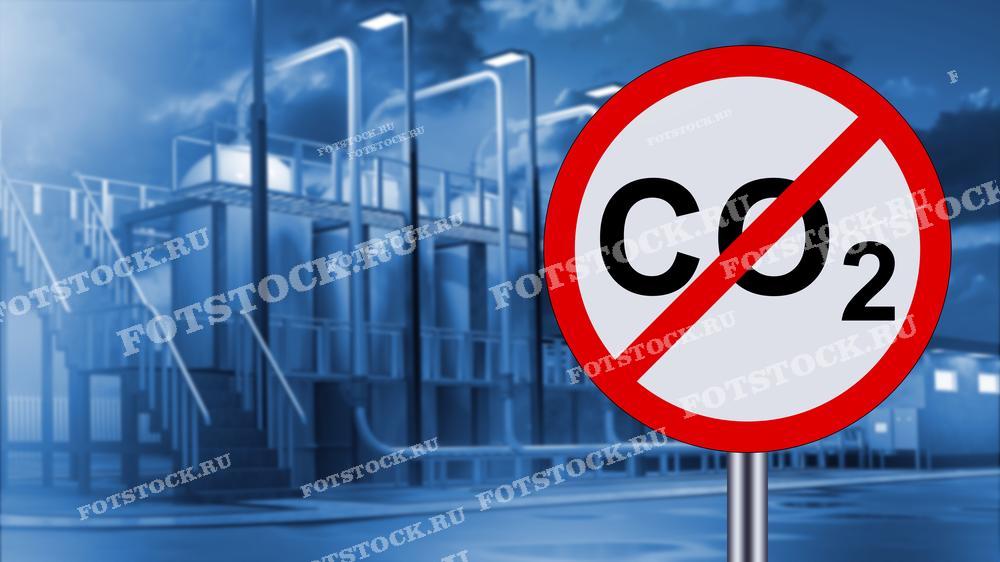 На фотографии изображен знак "Нет CO2" на фоне промышленного объекта, символизирующий стремление к снижению выбросов углекислого газа и защите окружающей среды. Снимок подчеркивает важность экологически чистых технологий и усилий по минимизации воздействия промышленности на климат.