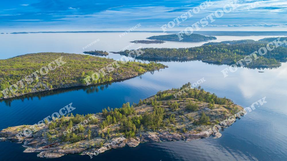 На фотографии изображены шхеры Ладожского озера, утопающие в зелени лесов. Снимок сделан с высоты, что позволяет увидеть живописные островки и гладкую поверхность воды. Ладога — крупнейшее озеро Европы, привлекает туристов своей природной красотой и возможностями для активного отдыха. Это место идеально подходит для путешествий и наслаждения природой Карелии.