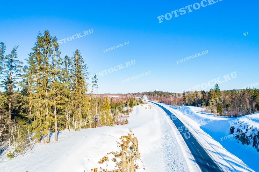 На фотографии изображена зимняя автодорога в Карелии, которая проложена через лесные массивы. По краям дороги возвышаются величественные сосны и ели, а окружающие леса покрыты снежным покровом. Дороги Карелии не только живописны, но и являются важной частью туристических маршрутов, ведущих к природным достопримечательностям региона.
