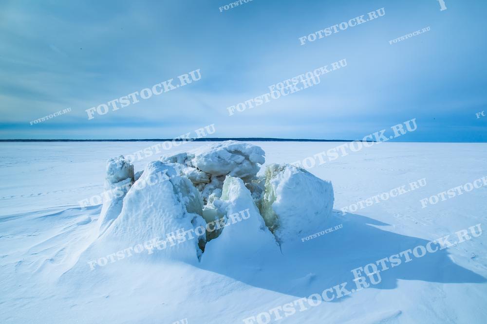 На фотографии изображен зимний пейзаж Ладожского озера с ледяными торосами, которые образовались на заснеженной поверхности озера. Эти ледяные глыбы представляют собой характерное явление для зимней Карелии, когда сильные ветры и морозы превращают поверхность озера в суровую, но красивую картину. Ладожское озеро зимой привлекает туристов своей величественной и почти нереальной атмосферой, где можно ощутить силу и мощь природы.