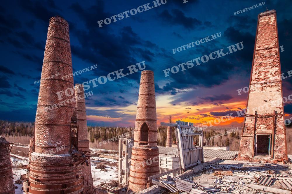 На фотографии изображены заброшенные кирпичные трубы Итальянского завода в Карелии на фоне яркого заката. Старые сооружения, оставшиеся от былых времён, создают атмосферу истории и запустения. Красочное вечернее небо контрастирует с руинами, подчеркивая их величие и значимость. Итальянский завод в Рускеале - одно из исторических мест Карелии, привлекающее внимание туристов и любителей истории.