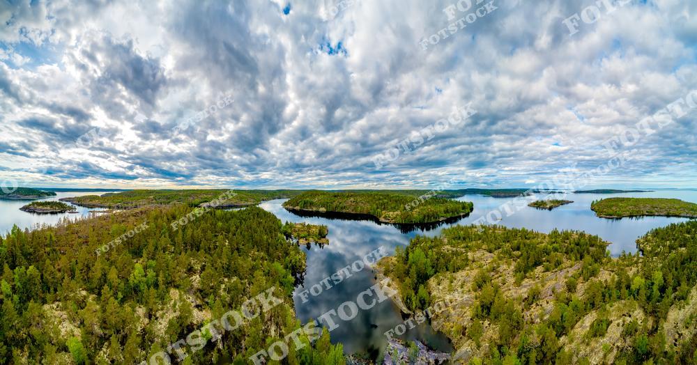 Фотография сделана с высоты птичьего полёта и демонстрирует красоту Ладожских шхер — уникального природного феномена в Карелии. На изображении видны многочисленные острова, покрытые хвойным лесом, и извилистые заливы Ладожского озера. Такие пейзажи характерны для прибрежной зоны в районе Сортавалы и Лахденпохьи, которые считаются туристическими центрами региона. Эта местность пользуется популярностью у путешественников, предпочитающих активный отдых и исследование природы Карелии с воды и воздуха.