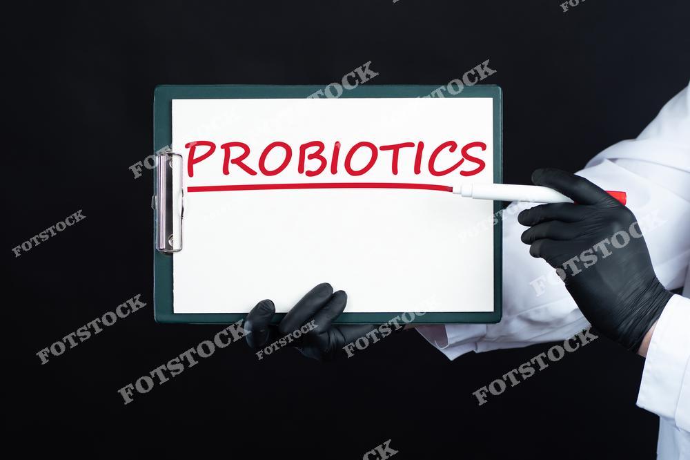 На фото изображен планшет с надписью "Probiotics", выделенной красной линией. Рука в черной перчатке держит маркер, подчеркивающий важность темы. Изображение символизирует внимание к пробиотикам и их значению для здоровья.
