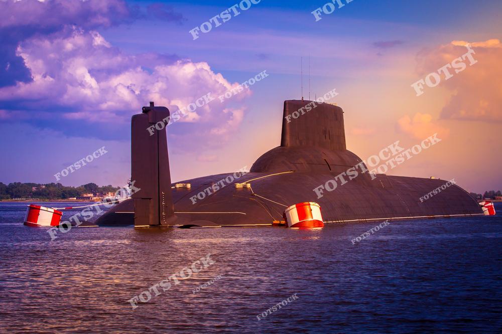На фотографии изображена подводная лодка, находящаяся на поверхности воды в лучах закатного солнца. Яркие краски неба и воды подчёркивают величие и силу судна. Снимок демонстрирует технологические возможности военно-морского флота.