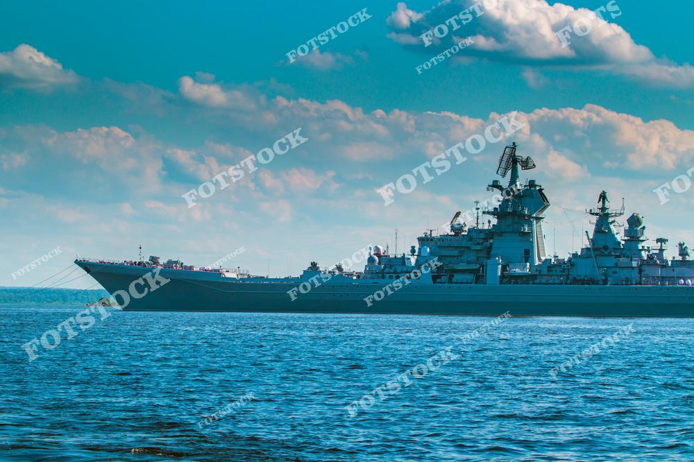 На фотографии изображён крупный военный корабль, плывущий по спокойному морю под голубым небом с облаками. Судно подчёркивает силу и технологическую оснащённость военно-морского флота. Снимок символизирует защиту и стратегическую значимость морских технологий.