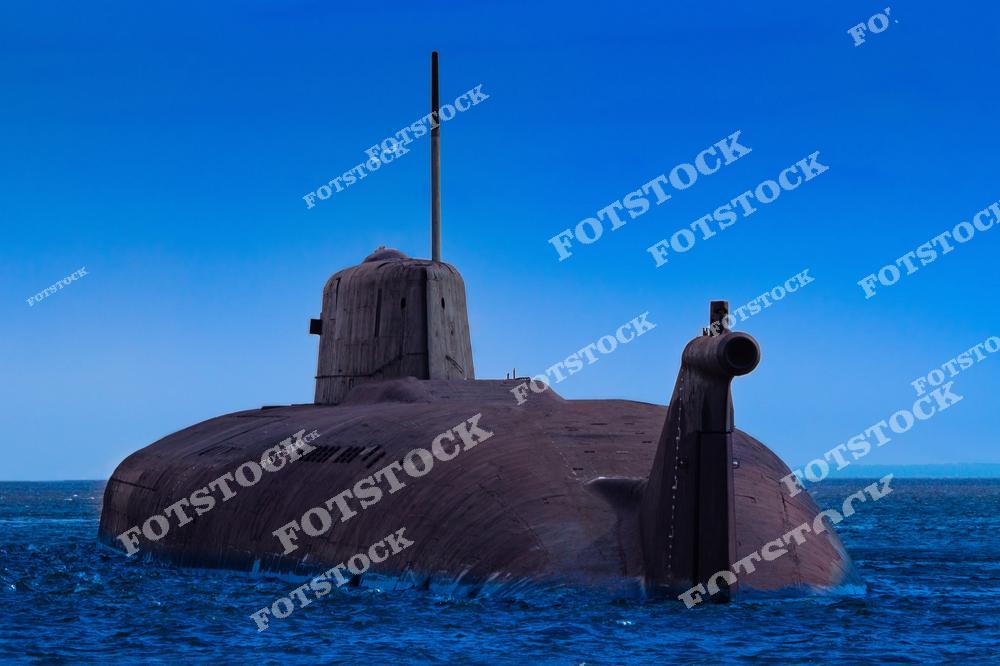На фотографии изображена подводная лодка крупным планом, находящаяся на поверхности воды. Глубокий синий цвет неба и воды подчёркивают внушительный облик судна. Снимок отражает современные технологии и мощь военно-морской обороны.