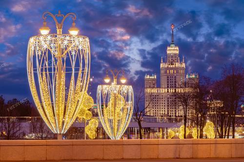 На этом снимке зимнего вечера в Москве отчетливо видны рождественские украшения, развешанные по улицам города. Панорама Москвы со сталинской высоткой воссоздает волшебство праздничной атмосферы. 
Этот снимок прекрасно иллюстрирует рождественскую атмосферу столицы России и может быть использован для создания праздничных открыток, а также в статьях и рекламных материалах, связанных с зимним отдыхом в Москве и новогодними мероприятиями.