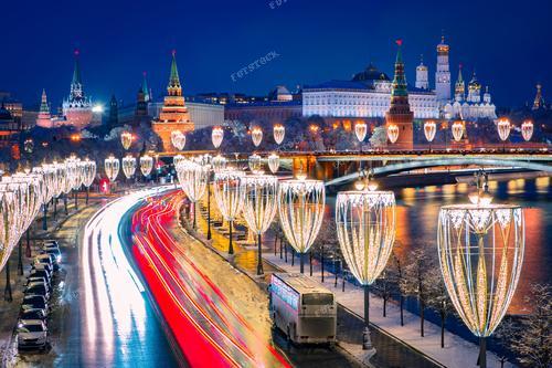 Это фото представляет зимний вечер в Москве, запечатленный квадрокоптером с высоты. Огоньки фонарей, украшенных рождественской иллюминацией, добавляют уюта этому зимнему пейзажу. Фотография иллюстрирует динамичность и красоту столичных улиц в праздничный вечер. Это изображение может быть использовано для иллюстрации статей о зимних городских пейзажах, а также в рекламе туристических поездок в Москву.