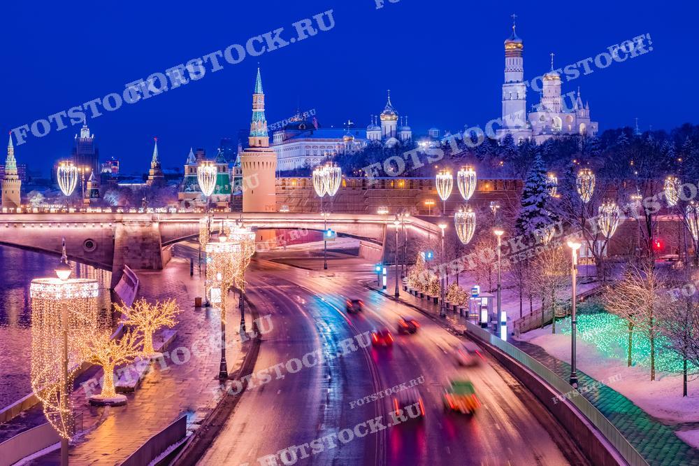 На фотографии изображена новогодняя иллюминация на набережной Москвы-реки с видом на Кремль. Светящиеся украшения и огни города создают праздничную атмосферу зимней Москвы. Фотография подходит для использования в материалах о новогодних праздниках, туристических буклетах и статьях о зимней Москве.
