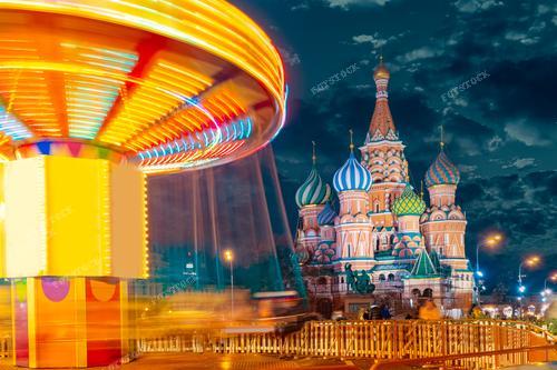 На фотографии запечатлён новогодний яркий вечер в Москве. Рядом с Собором Василия Блаженного детская карусель создает атмосферу веселья и праздника. 
Эта фотография прекрасно подходит для иллюстрации новогодних событий, детских праздников, туристических проспектов и рекламы городского отдыха. Она передаёт тёплую атмосферу зимних вечеров и радостные моменты на праздничных улицах столицы России.