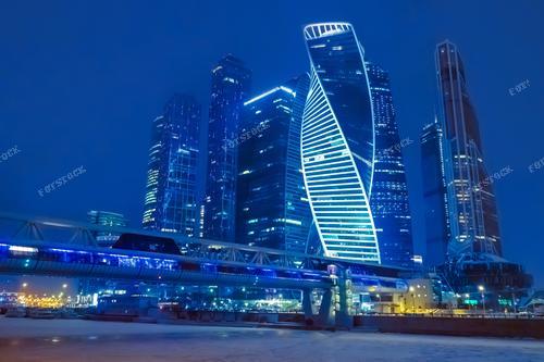 На фотографии запечатлен зимний вечер в Москве с впечатляющим видом на небоскребы. 
Эта фотография подходит для использования в печатных и онлайн изданиях, привлекая внимание к современной архитектуре Москвы и красоте зимнего пейзажа.