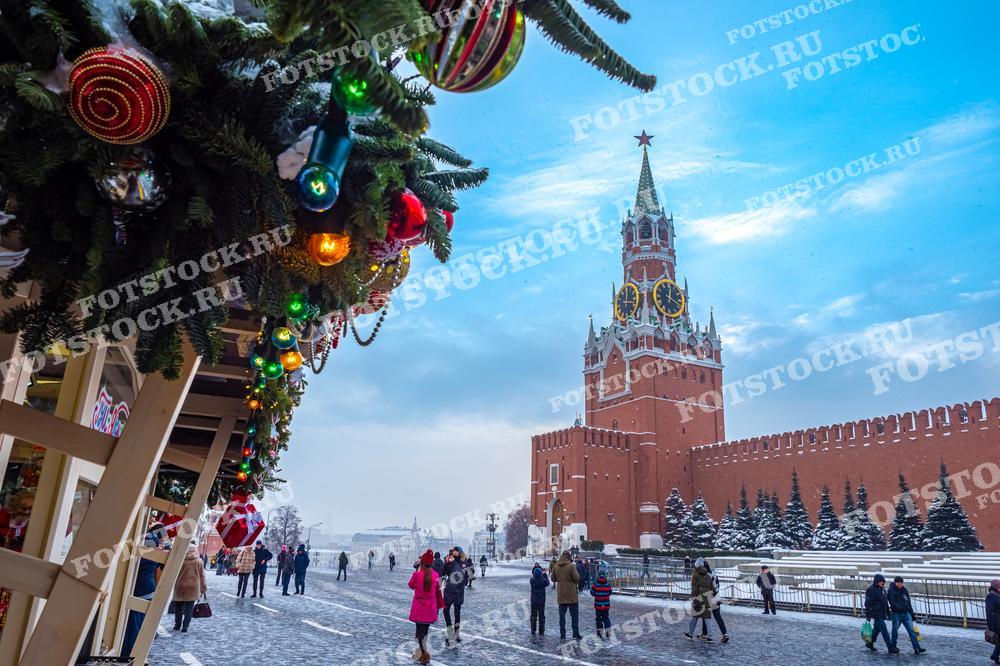 На фотографии запечатлены сверкающие огоньки и украшения, придающие столице России особый шарм в преддверии праздничного вечера. Кремлевская набережная украшена в честь Рождества, и иллюминация создает уютную атмосферу ожидания праздника. Огни Кремля и городской пейзаж вокруг иллюстрируют зимнюю сказку, которую можно использовать в печатных изданиях о путешествиях, новогодних открытках, а также в рекламных материалах, привлекая внимание к туристическим направлениям в России.