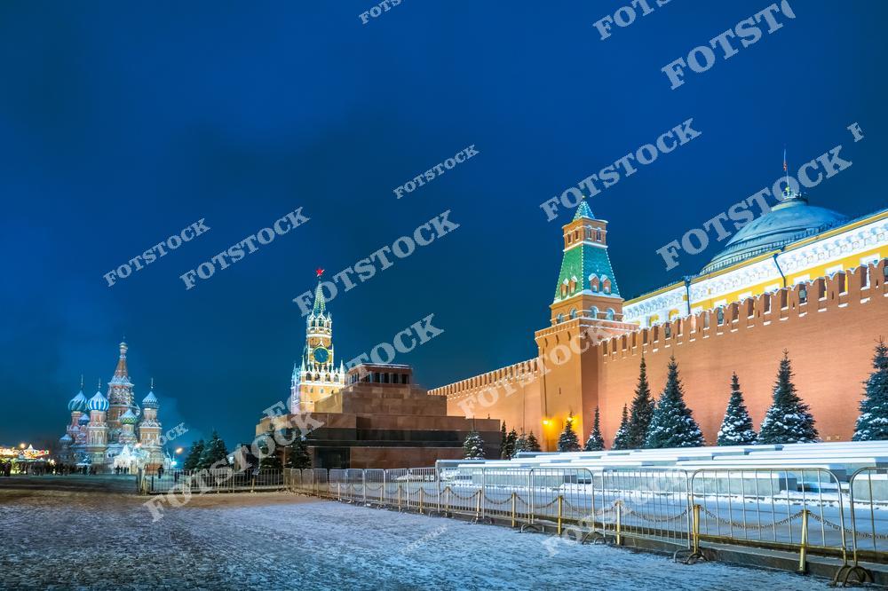 На фотографии изображён зимний Кремль в Москве, с красивым видом на Красную площадь. На переднем плане — Спасская башня, которая украшена огнями. Вдалеке видна уникальная архитектура собора Василия Блаженного, а также мавзолей Ленина. Всё покрыто снегом, что придаёт особую атмосферу зимней ночи. Улицы и здания в центре Москвы украшены световыми гирляндами, а мягкий свет создаёт тёплую атмосферу в холодный зимний вечер.