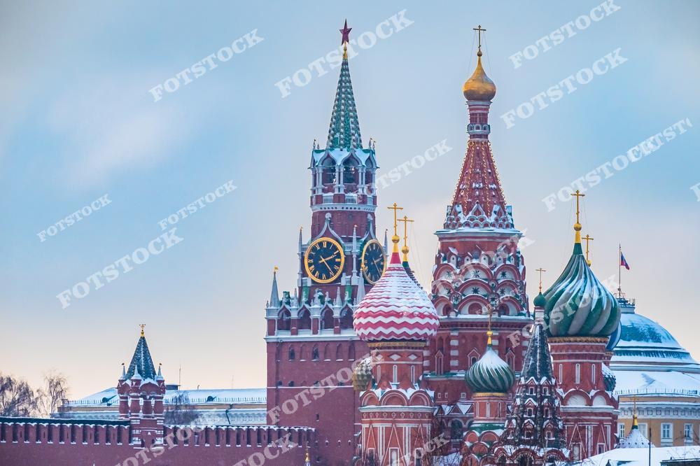 На фотографии изображены главные символы Москвы — Собор Василия Блаженного и Спасская башня Кремля. Купола собора покрыты снегом, добавляя зимней сказочности к их яркому оформлению.