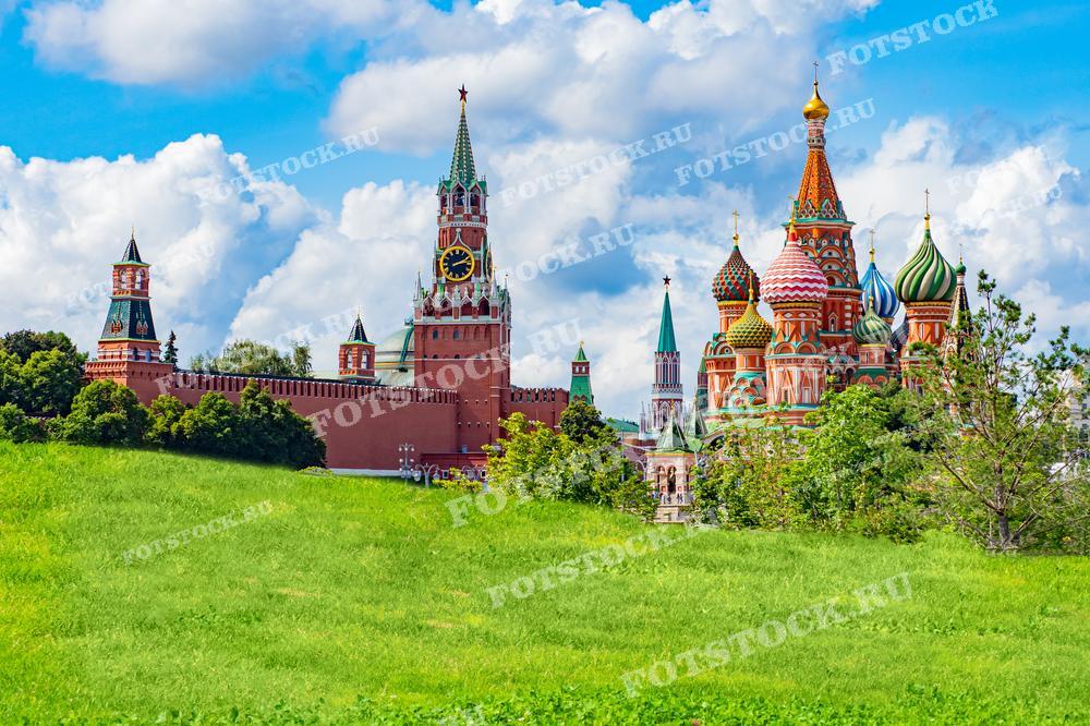 На фотографии изображены Спасская башня и Собор Василия Блаженного в Москве на фоне голубого неба с облаками. Фото можно использовать для иллюстраций, рекламы и туристических материалов.