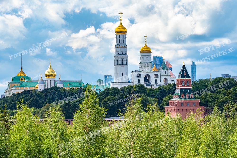 На фотографии изображены Московский Кремль и колокольня Ивана Великого, находящиеся в центре Москвы. Зелень перед стенами Кремля подчеркивает летний день и чистое небо.