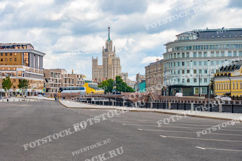 На фотографии изображена улица в центре Москвы с одной из сталинских высоток. Яркий летний день подчеркивает архитектурные детали зданий и спокойную атмосферу города.