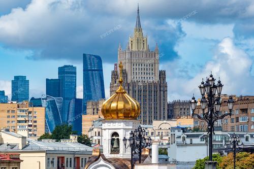 На фотографии запечатлён пейзаж Москвы с выдающимися зданиями. Архитектура столицы России предстаёт перед зрителем во всей своей величественной красоте. Крыши зданий, горизонт города и даже купол храма создают атмосферу умиротворённости и величия российской столицы.