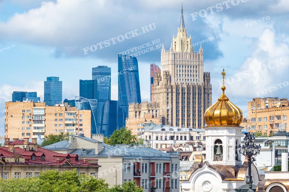 На фотографии изображён контраст старой и новой архитектуры Москвы. На переднем плане видна золотая купольная часть православной церкви, а за ней — типичные московские жилые дома. На заднем плане возвышаются знаменитые сталинские высотки и современные стеклянные небоскрёбы Москва-Сити, демонстрирующие динамику развития столицы. Эта фотография может использоваться в культурных и архитектурных публикациях, образовательных материалах, а также в туристических брошюрах, чтобы показать разнообразие городской застройки Москвы.