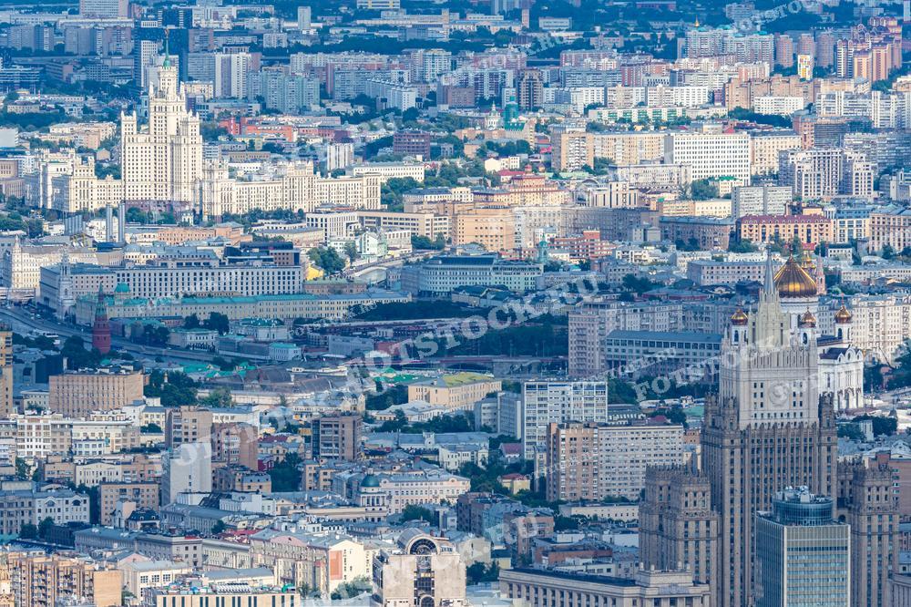 На фотографии изображена панорама Москвы с высоты, видны сталинские высотки, а также множество других жилых и административных зданий. Фото можно использовать для иллюстраций, рекламы и туристических материалов.