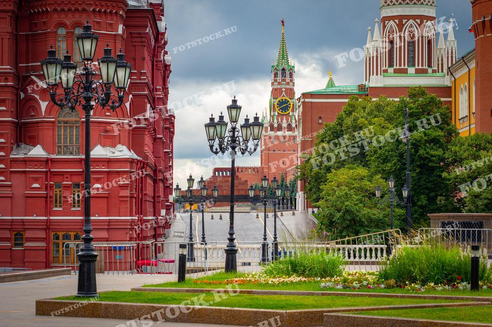 На фотографии изображена Спасская башня Кремля и Красная площадь. Справа виден Государственный исторический музей с его красными стенами и декоративными элементами. Летний день подчеркивает архитектурное величие центра Москвы.