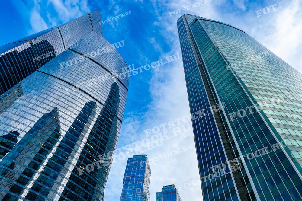 На фотографии изображены небоскребы делового центра Москва-сити. Высотные здания отражают голубое небо, создавая впечатляющий вид современной архитектуры столицы России.