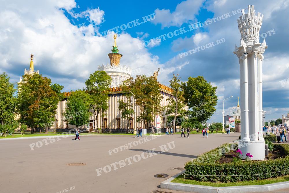 На фотографии изображены павильоны на территории ВДНХ в Москве. Видна архитектура советского периода с золотыми элементами, символизирующими богатство и достижения народного хозяйства.