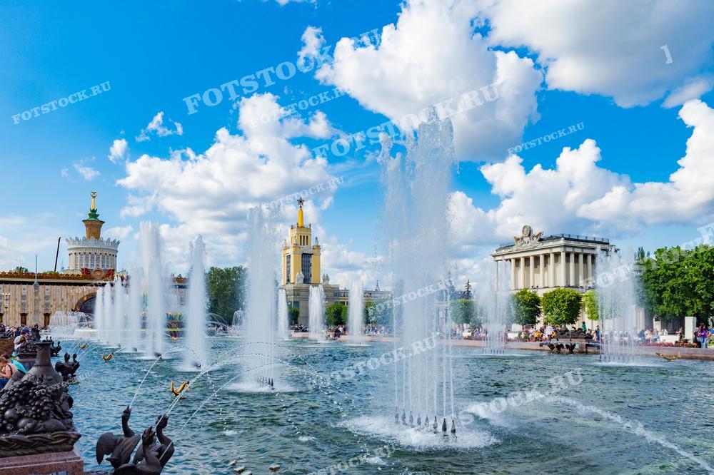 На фотографии изображён фонтан в ВДНХ в Москве, окружённый знаковыми зданиями советской архитектуры. Это место популярно среди туристов и жителей города, идеально подходит для прогулок и отдыха, а также часто используется в качестве места для фотографий и культурных мероприятий.