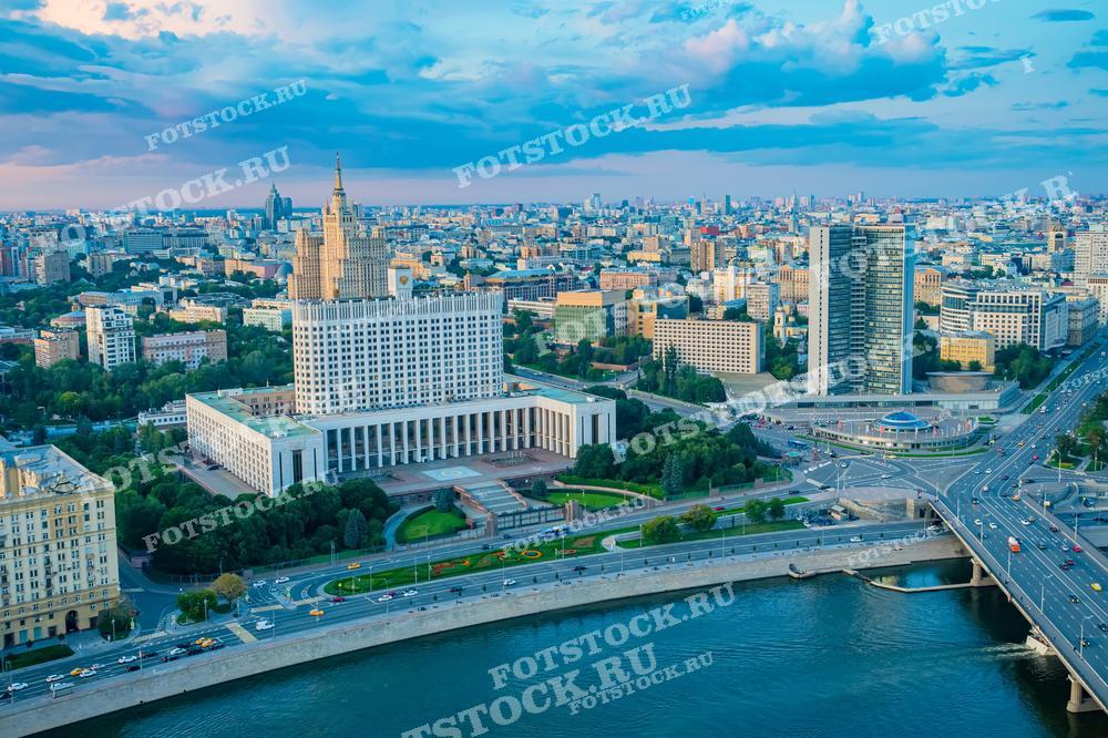 На фотографии изображена вечерняя панорама с видом на Дом Правительства России и Москву-реку.