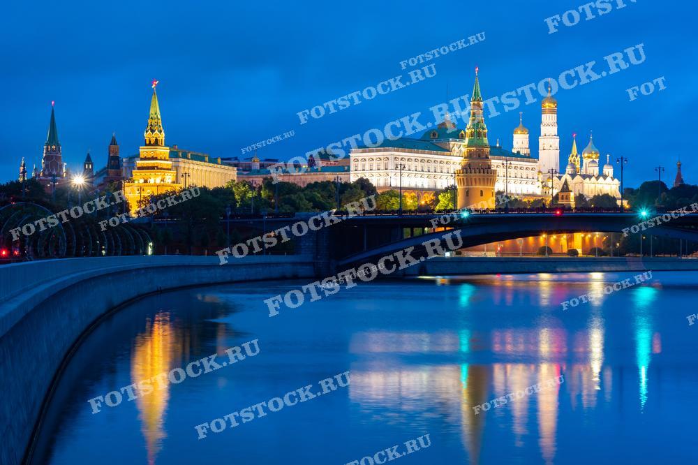 Фотография ночного Кремля и реки Москвы с мостом, освещённых яркой подсветкой. Подходит для использования в материалах о ночной Москве, её достопримечательностях и городской архитектуре.