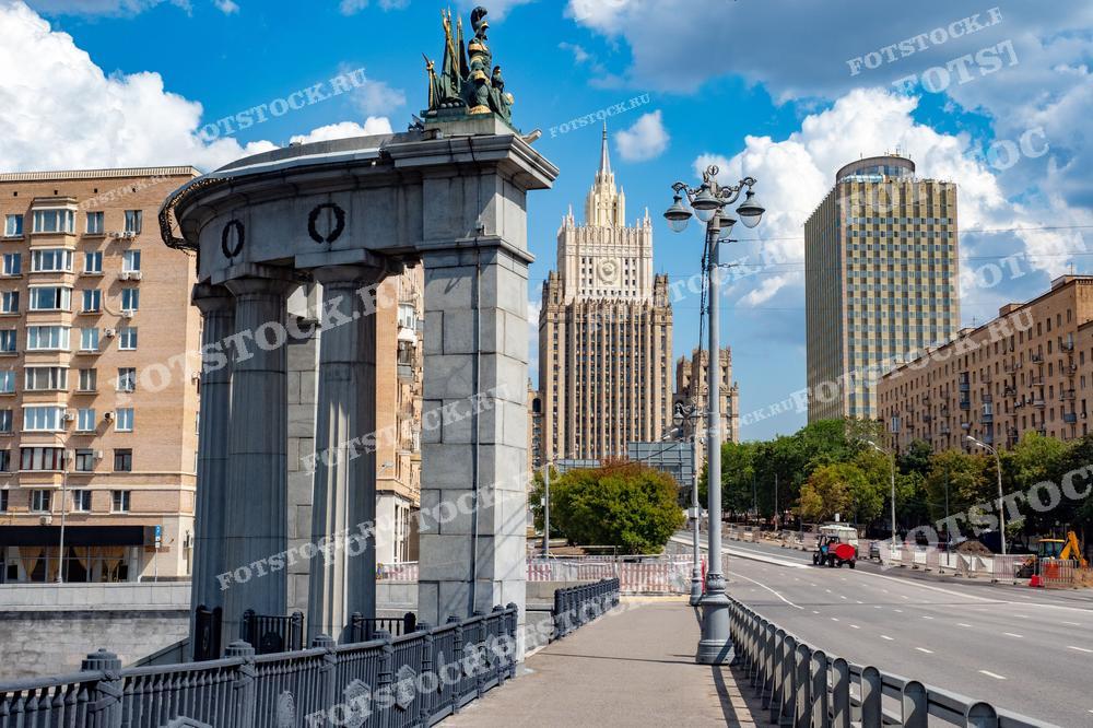 Фотография запечатлела один из символов Москвы — сталинскую высотку Министерства иностранных дел России, возвышающуюся над городом. Слева частично видна арочная конструкция Бородинского моста, добавляющая глубину композиции и подчёркивающая контраст между исторической и современной архитектурой столицы. Этот снимок отлично подойдёт для иллюстрации туристических гидов по Москве, публикаций о знаковых архитектурных объектах города, а также для образовательных материалов, посвящённых архитектуре и истории Москвы.