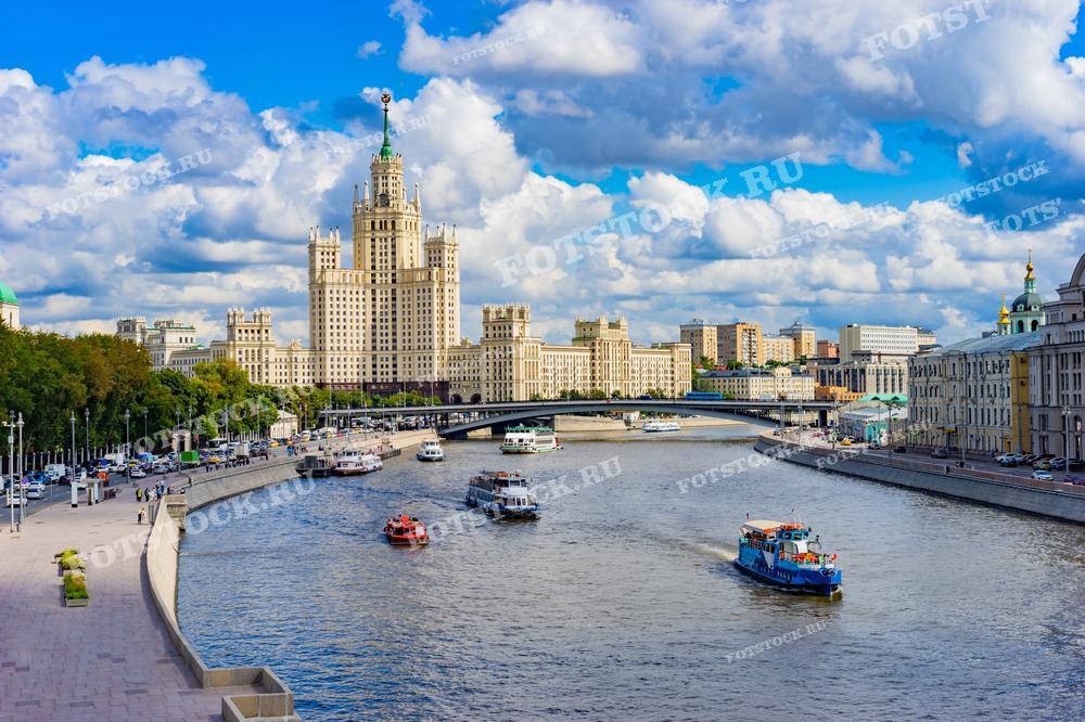 На фотографии изображена одна из семи сталинских высоток — жилой дом на Котельнической набережной в Москве. Снимок выполнен в ясный день, река Москва живописно изгибается, создавая красивый вид на городскую набережную с многочисленными прогулочными катерами. Это изображение может использоваться в туристических гидах, образовательных материалах о московской архитектуре, а также в публикациях, посвященных городскому планированию и развитию.