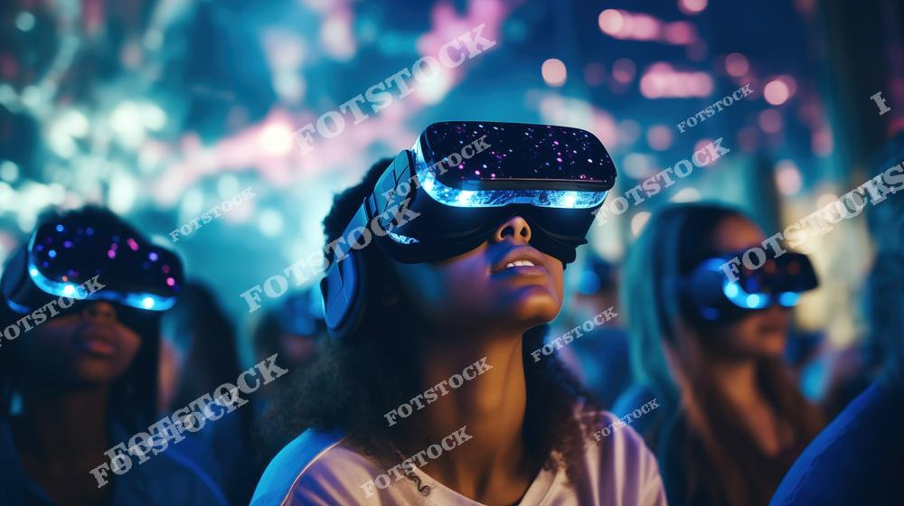 На фотографии изображена группа людей в VR-очках, наслаждающихся захватывающим опытом виртуальной реальности. Яркие огни и неоновый фон создают футуристическое настроение и погружение в цифровую среду. Фотография отражает современное использование технологий для развлечений и обучения.