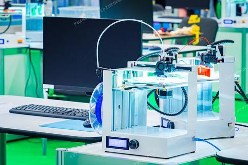 На фотографии изображены два профессиональных 3D-принтера, установленных рядом с компьютером. Эти устройства предназначены для создания трехмерных деталей и компонентов для промышленных нужд. Фото иллюстрирует применение передовых технологий в области трехмерной печати, особенно в дизайн-студиях.

Эта картинка посвящена передовым методам печати. Студенты, инженеры и дизайнеры могут использовать данное изображение для визуализации процесса создания инновационных продуктов и прототипов.

Также, фото может быть использовано компаниями, занимающимися продажей оборудования для трехмерной печати, в рекламных материалах, подчеркивая высокотехнологичное оборудование.