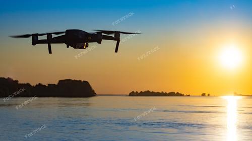 Фотография запечатлевает великолепный момент – полет беспилотника над водной гладью на фоне заходящего солнца. Панорама озера в лучах заката создает завораживающий вид. Квадрокоптер совершает увлекательные съемки, захватывая красоту заката. Фото иллюстрирует хобби – управление квадрокоптером и создание качественных снимков с воздуха.

Эта фотография может использоваться для рекламы дронов, техники для аэросъемки, а также для иллюстрации статей о фотографии, туризме и современных технологиях. Она передает атмосферу свободного полета и восторга от красоты природы.